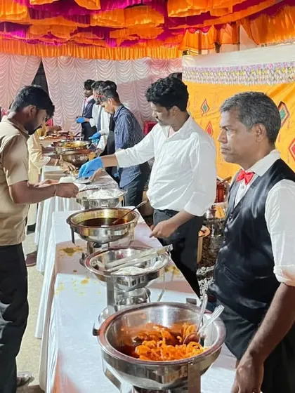 Guests being served at a buffet line during a busy haldi event. My staff ensures the food trays are always full and the service is quick.