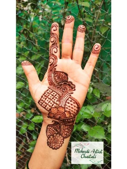 A classic Arabic 'bel' or vine design. This pattern flows diagonally across the hand, adorned with spirals on the fingertips, making it a popular choice for guests.