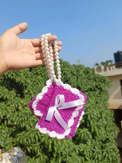 The purple mini purse shown with its pearl strap. This small detail adds a touch of elegance to the design.