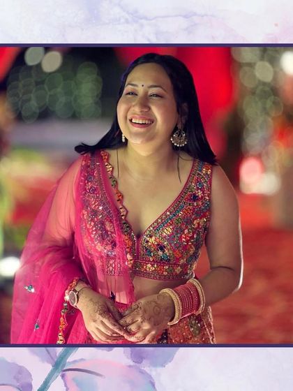 A client's smile says it all. She looks joyful and beautiful in a multi-colored blouse and pink lehenga.