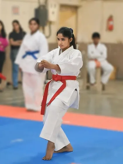 A student demonstrates a karate form with sharp, clean movements. Her red belt signifies her advanced understanding of Shito Ryu principles.