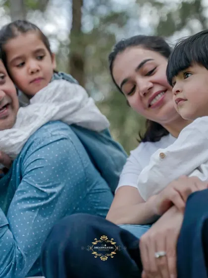 A happy family of four enjoying a candid moment together while sitting outdoors.