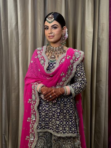 A full-length shot of the bride, her hair in a neat bun complementing her regal outfit.
