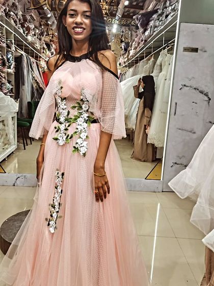 A smile that says it all! This client is glowing in her custom pink gown, featuring a cascade of white and green floral appliqués that we designed just for her.