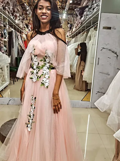 A smile that says it all! This client is glowing in her custom pink gown, featuring a cascade of white and green floral appliqués that we designed just for her.