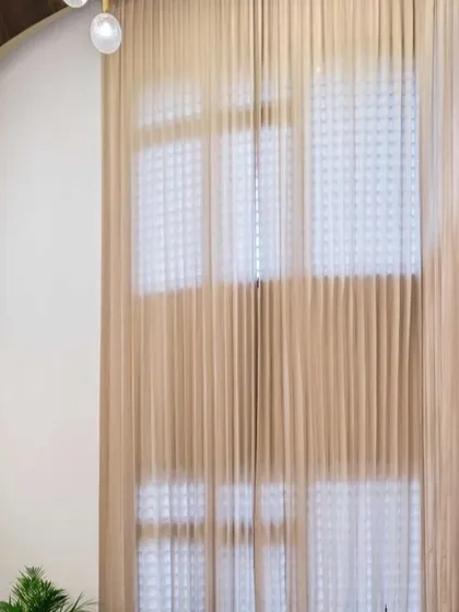 The dramatic, double-height curtains in this living space soften the grand scale of the room while providing privacy. This detail adds a layer of elegance and texture.