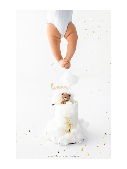 A creative and artistic shot for a half birthday celebration. The focus on the tiny feet dangling over a beautiful milestone cake creates a unique and memorable image.