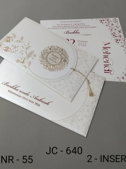 A clean white invitation with a unique semi-circular flap and a decorative tassel. The design is modern and elegant, with inserts for your Mehendi and other events.