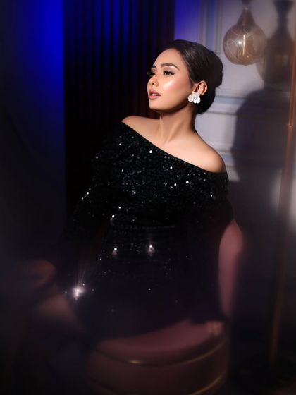 An elegant pose under dramatic blue lighting, highlighting the contours of the face and the chic updo.