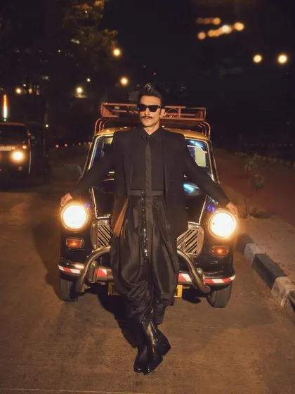 A wide shot of Ranveer with the iconic kaali-peeli taxi. The styling was designed to be both high-fashion and grounded in a cool, urban Mumbai context.