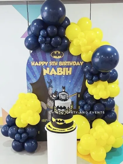 A compact Batman themed 5th birthday setup. This decoration uses a character backdrop with a yellow and navy balloon garland, perfect for smaller spaces.