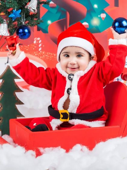 A joyful baby Santa playing with Christmas ornaments in his sleigh. These holiday mini-sessions are so much fun.