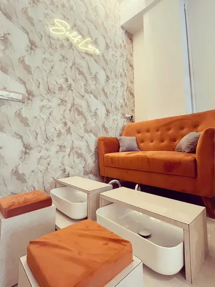 This is where the relaxation happens. Our pedicure station is designed for your comfort, with plush seating and a serene ambiance. We believe a great pedicure is a full sensory experience, complete with a 'Self Love' reminder.