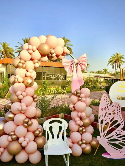 An angled shot of the pink and gold butterfly party, showing the beautiful arrangement of balloons and props in a sunny garden.