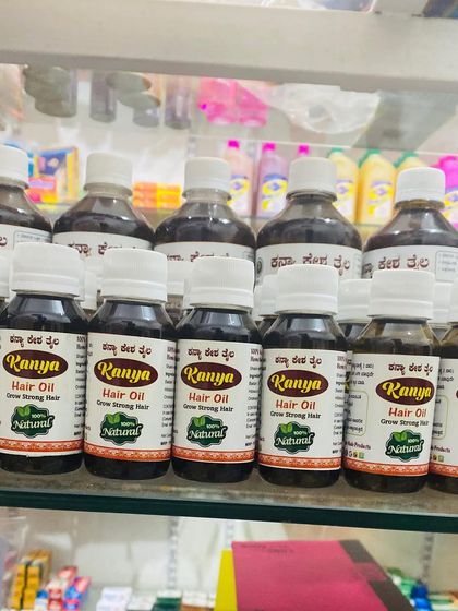 My Kanya Hair Oil bottles of different sizes, displayed on a glass shelf in a retail store.