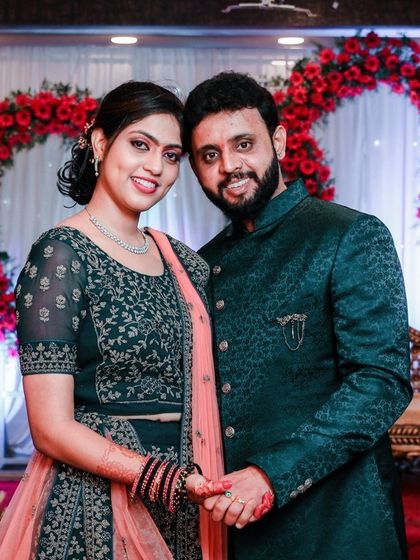 A happy couple posing against a heart-shaped floral backdrop at their reception, perfectly framing their love story.