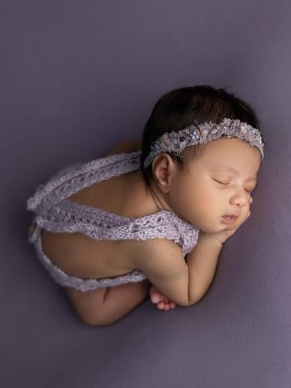 A beautiful top down view of the 'taco' pose, showing how the baby is curled up comfortably. The purple lace romper adds a lovely textural detail.