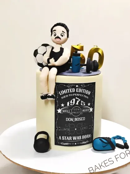 A fun and personalized 50th birthday cake for a fitness enthusiast. The design includes a fondant figure of the birthday person, along with a football, kettlebell, and other gym-related items.