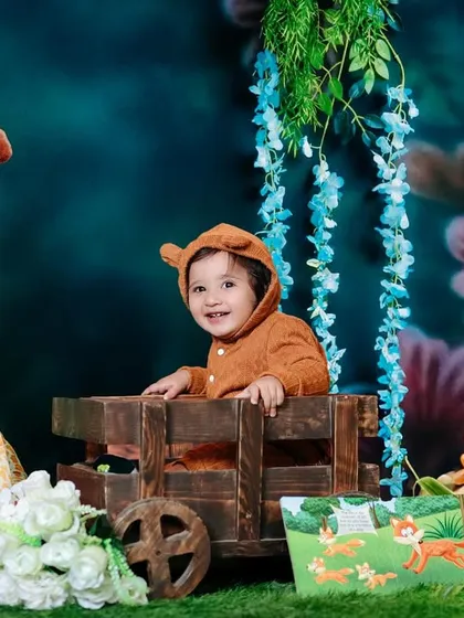 Such a big miracle in such a small person. A cute baby in a bear hoodie sits in a wooden cart in our jungle-themed studio.