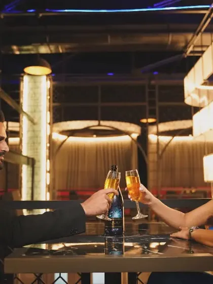 A sophisticated pre-wedding shot of a couple toasting with champagne in a stylish restaurant, perfect for an elegant, urban-themed shoot.