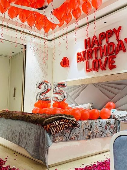 A full view of a 25th birthday room surprise. We used hundreds of red balloons on the ceiling, "Happy Birthday Love" foil letters, and a path of rose petals leading to the bed.