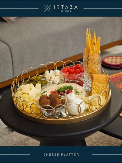 A stylish and modern cheese platter served on a gold-rimmed tray, showcasing a variety of textures and flavors from creamy hummus to crunchy breadsticks.