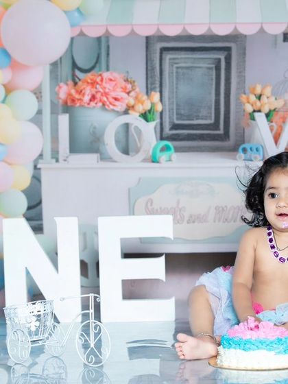 A full view of the first birthday setup, with a beautiful pastel balloon arch and a happy baby.