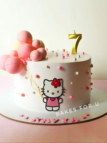 A sweet Hello Kitty cake for a 7th birthday, featuring the iconic character and a cascade of pink chocolate balloons.