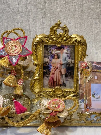 A personalized engagement hamper featuring a photo of the couple in an ornate golden frame. The tray is decorated with traditional gota patti work, blending personal touches with cultural elegance.