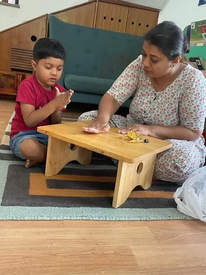 A teacher and child work together on a clay modeling activity during our summer camp, demonstrating our hands-on, guided approach to learning.