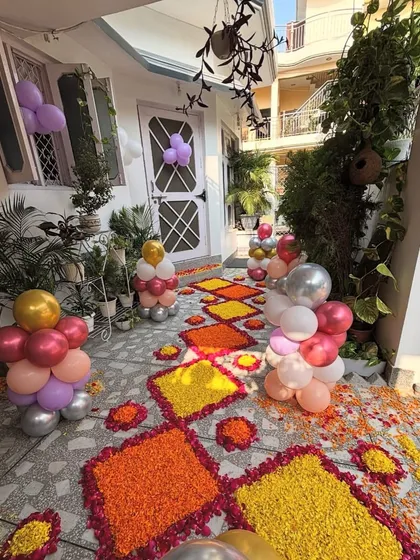 A beautiful entrance decoration to welcome a new baby. The pathway is decorated with flower rangoli and small balloon bunches.