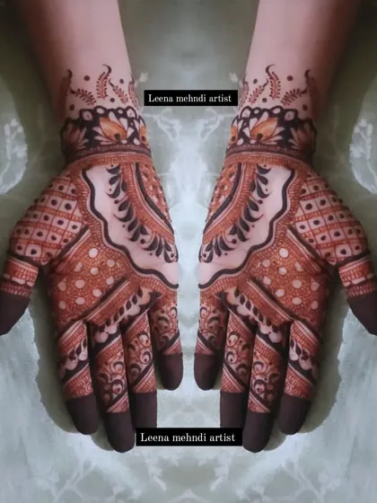 A striking design that uses bold, dark-filled patterns to create a strong visual impact. The intricate check patterns on the fingers and palms contrast beautifully with the flowing motifs on the back of the hand.