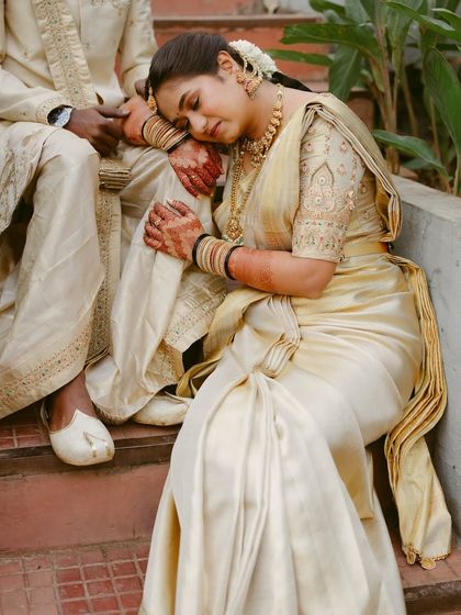 A peaceful moment captured between a couple in elegant cream and gold attire. The bride's serene expression as she rests on her partner speaks volumes.