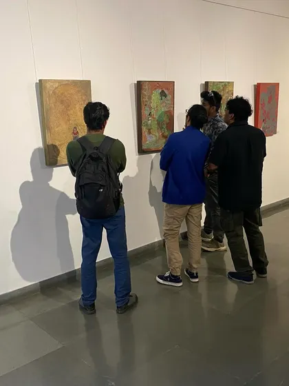 Visitors studying the details of Unnikrishnan C's paintings.