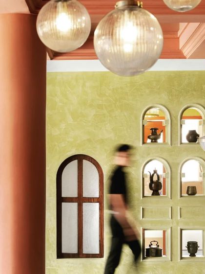 Arched niches display antique brass artifacts, adding a touch of history and authenticity. The lime-plastered walls provide a textured, tactile quality to the space.