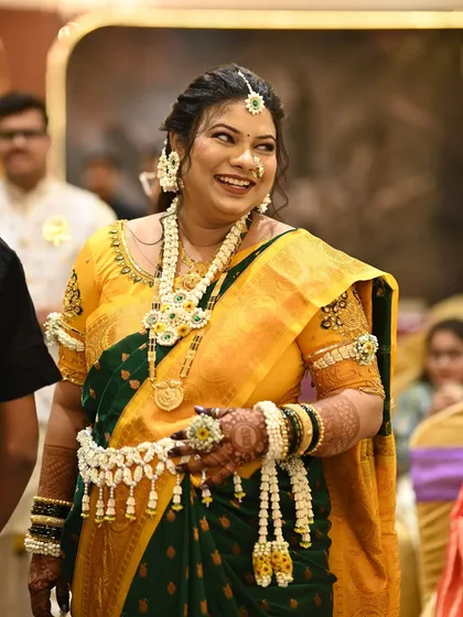 The joy of the occasion is captured in this photo. The client's floral jewellery, made with jasmine buds and yellow flowers, shines as she smiles.