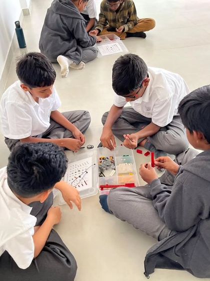 A team of students from Sadhu Vaswani International School works on the floor, completely absorbed in their LEGO challenge.