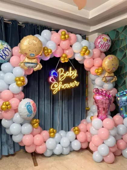 A classic baby shower balloon ring with a mix of pink and blue. The "Baby Shower" neon sign, along with baby-themed foil balloons, makes it a perfect photo corner for guests.