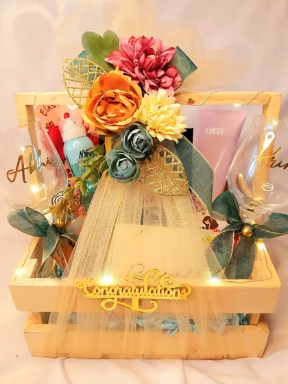 A perfect wedding gift hamper to congratulate the happy couple. This one includes personalized wine glasses, pampering goodies, and a custom 'Congratulations' sign, all packed in a lighted wooden crate.