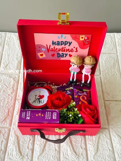 A cute Valentine's gift in a red suitcase box. This hamper includes a couple figurine, an "I love you" clock, and chocolates.