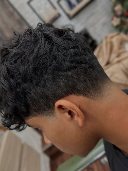 From another angle, you can see how the taper fade cleans up the edges while letting the curls on top be the main feature. This is a great style for clients who want a sharp but natural look.