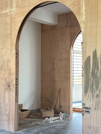 The journey from a raw plywood frame to a finished, fabric-wrapped archway. This before-and-after view highlights the structural planning and meticulous craftsmanship required to create the soft, transitional moments that define the Moire studio.