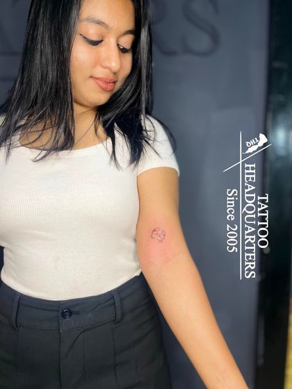 A small, minimalist zodiac symbol tattoo on the inner elbow.