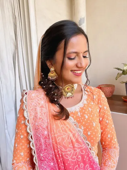 A happy, smiling client with her natural glow look. The soft makeup and braided hairstyle create a youthful and fresh appearance.