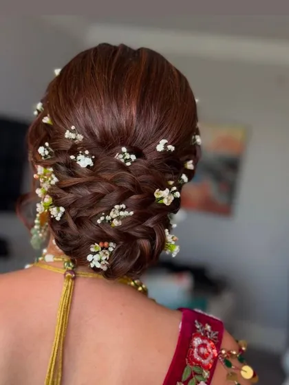 An intricate braided bun adorned with delicate baby's breath flowers. This style is both romantic and sophisticated, ideal for a wedding or engagement.