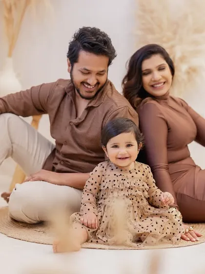 A happy family portrait from a first birthday milestone session. The smiles and relaxed poses show the genuine connection and joy of this beautiful family.