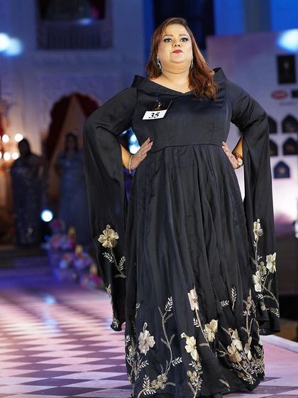 A black plus-size gown with dramatic bell sleeves and floral embroidery. It’s a unique and artistic piece for a special occasion.