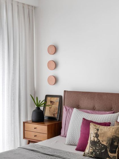 Art collection is a lifelong process. This bedroom corner shows how personal items, like the framed art and antique pillow, can be layered with modern furniture and decor to express individuality and create a cozy, farmhouse vibe.