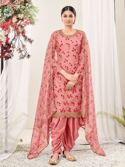 A modern take on a classic Punjabi suit. This chiku and pink net suit features a cape-style dupatta and dhoti pants, perfect for someone who loves to experiment with their style.