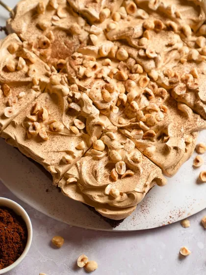 A top-down view of the finished Rum Soaked Dark Chocolate Traybake, generously covered with coffee mousse, toasted hazelnuts, and a dusting of cocoa powder.